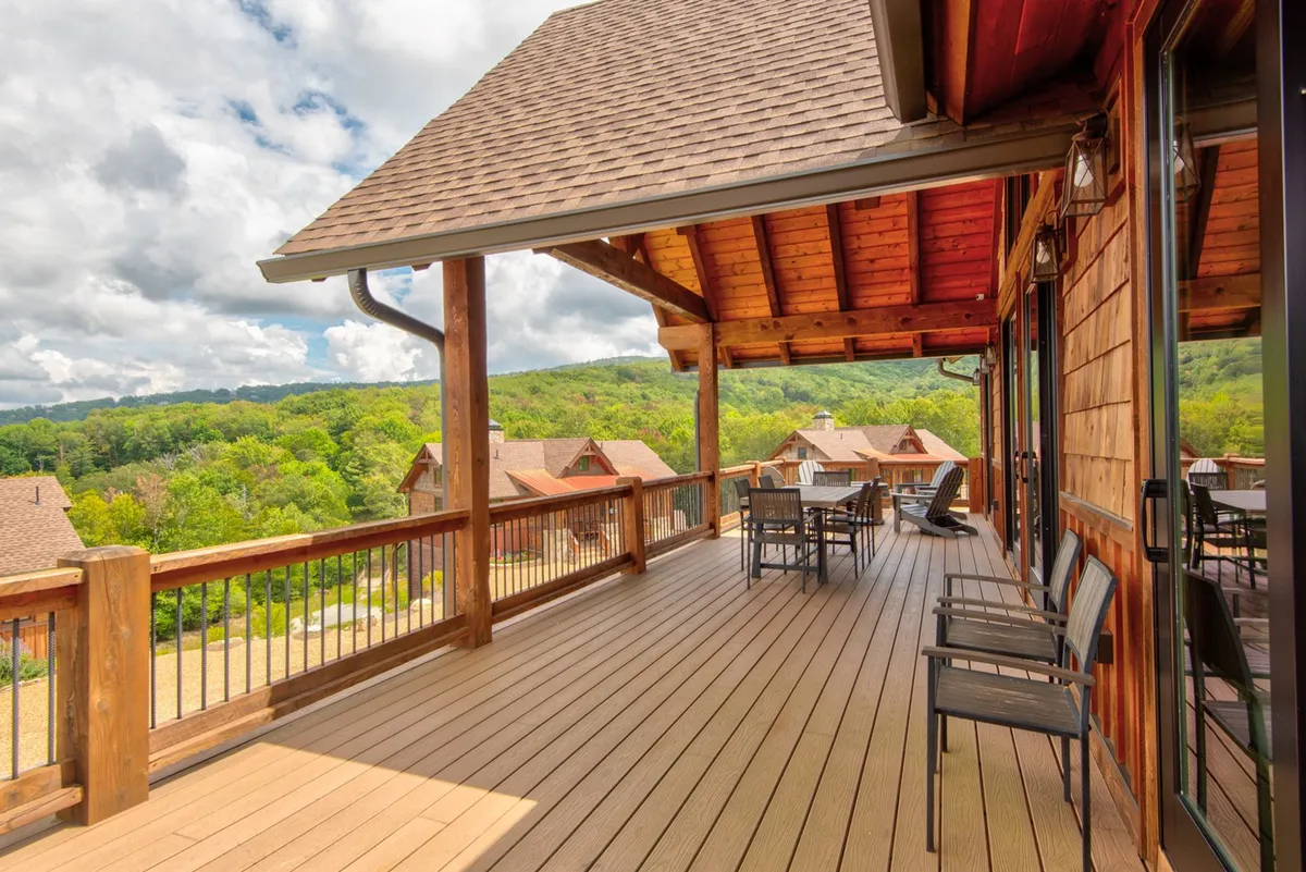 A spacious wooden deck overlooking lush greenery and rolling hills, furnished with comfortable outdoor seating. The scene suggests a quiet, intimate spot perfect for couples to share a meal or simply relax together while watching the sunset or savoring the peaceful landscape.